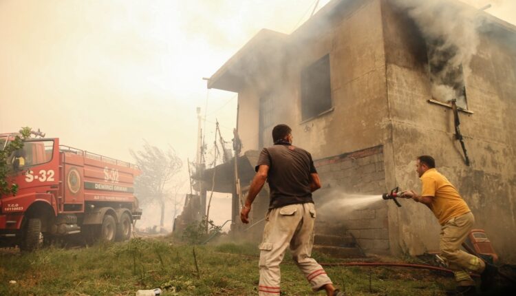 Locals and firefighters spray water on a burning house in Manavgat, Antalya, southern Turkey, July 29, 2021. (AA Photo)